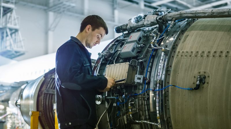 Aircraft mechanic inspecting a jet engine in a hangar